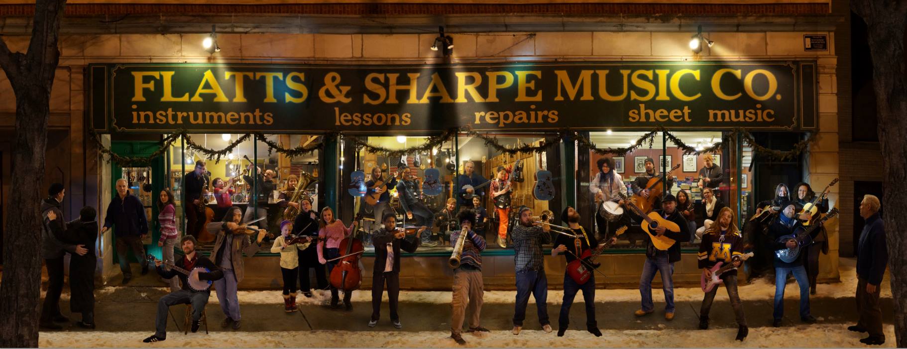 teachers and employees of the store hanging out front, playing their instruments against a lit up storefront at night