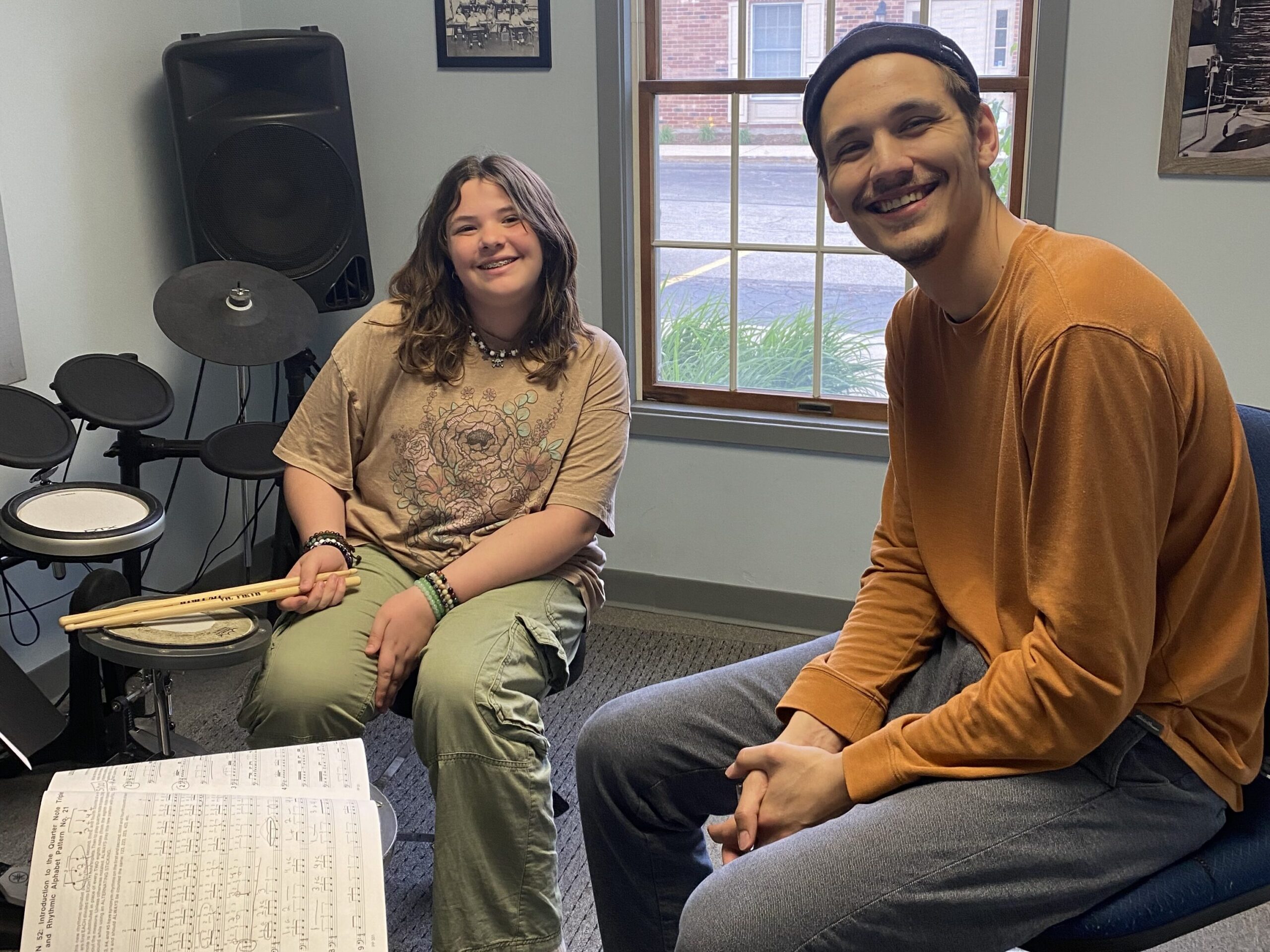 drum instructor and his student smiling at the camera during a lesson