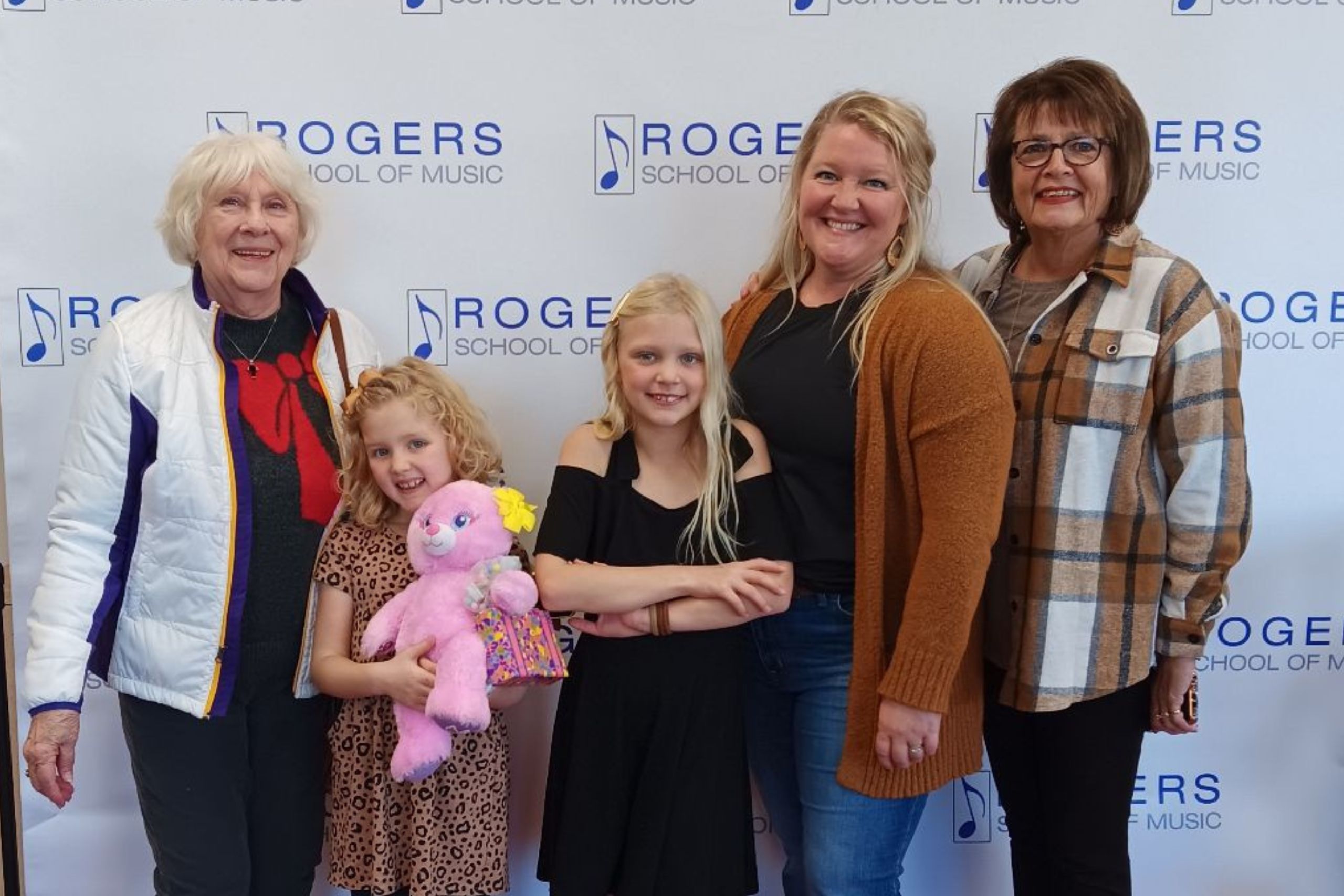 a family of women smiling against the Rogers step and repeat banner