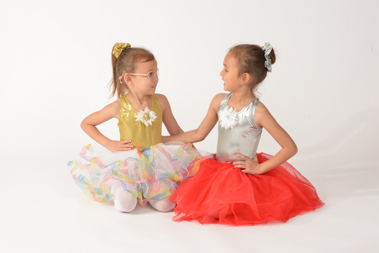 pair of young ballerinas smiling at each other