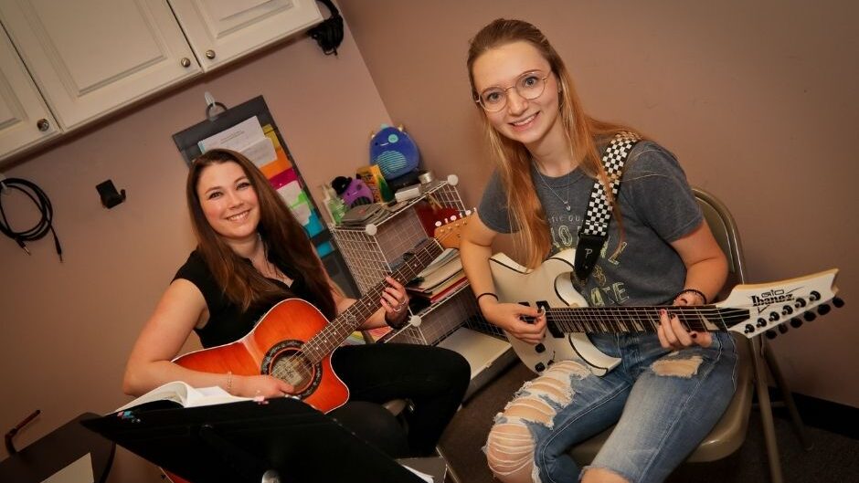 guitar teacher and student smiling at the camera