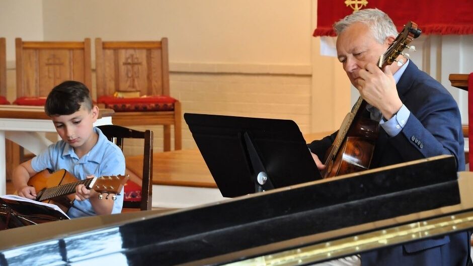 guitar teacher and student performing together during a recital 